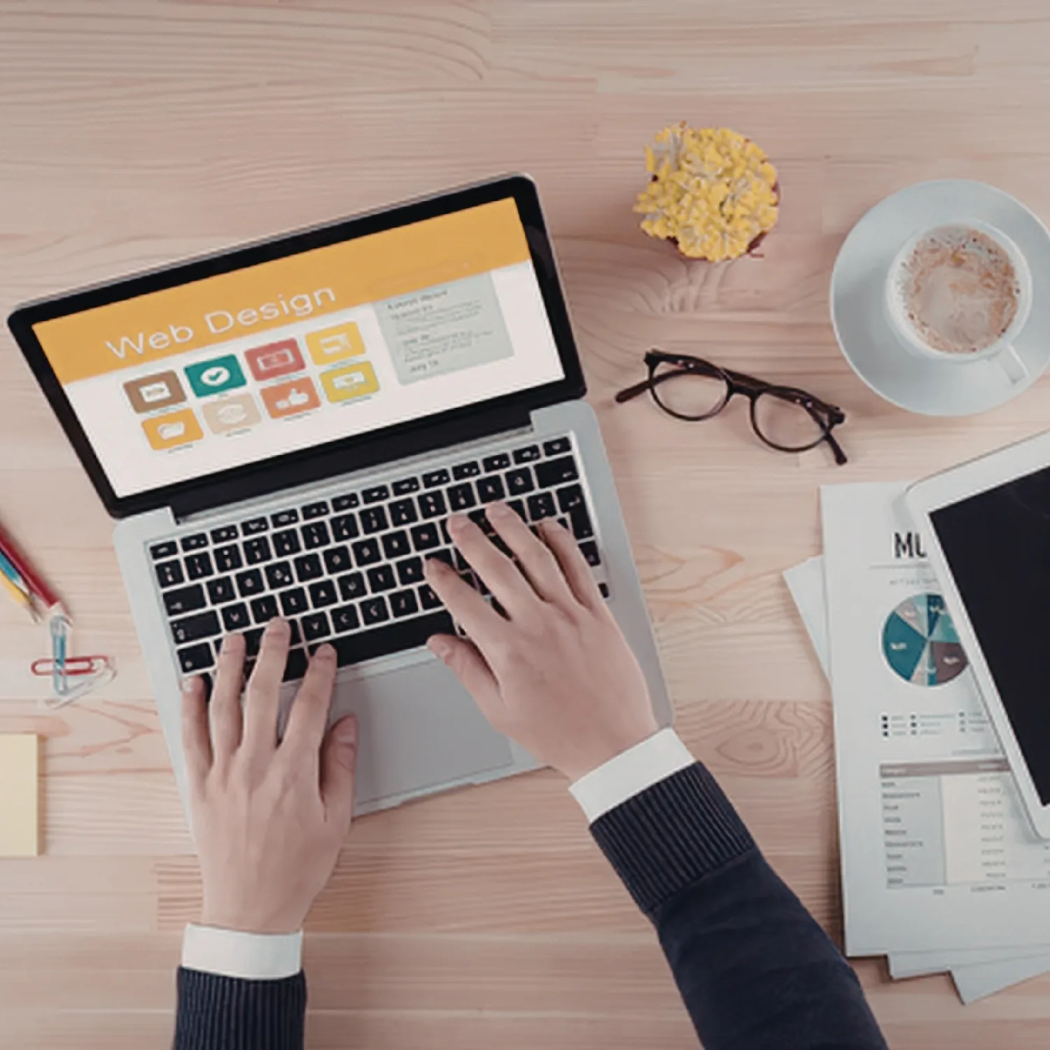 Overhead view of a designer working on a web design layout on a laptop